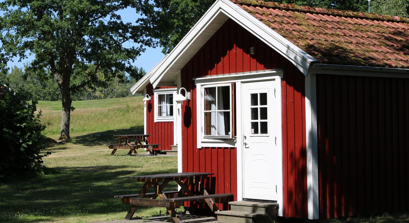 Röda campingstugor med vita dörrar och fönster.