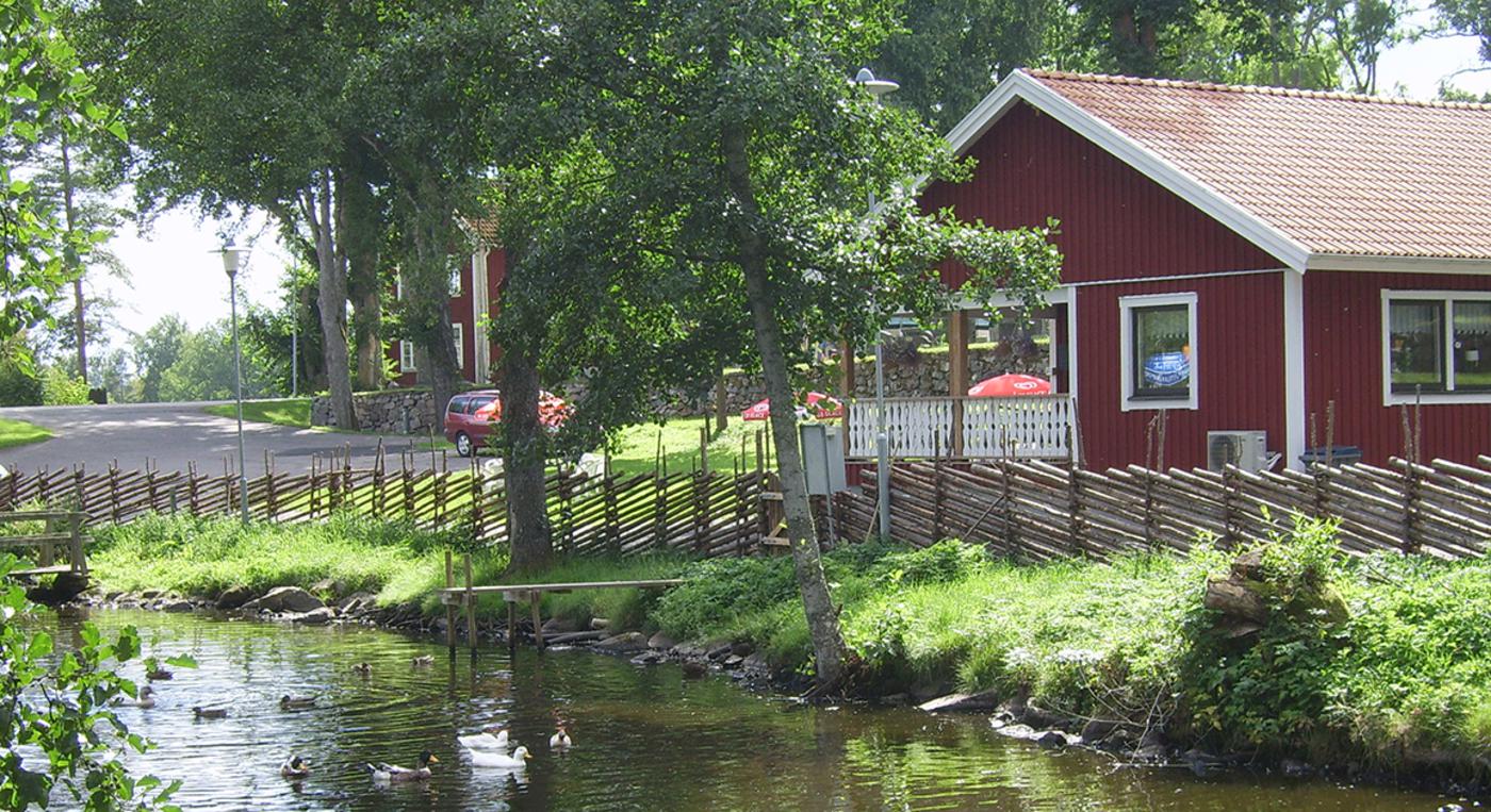 En röd byggnad intill en damm.