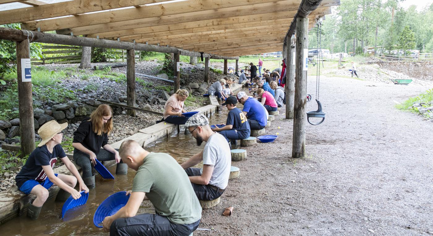 En samling personer vaskar guld i en bäck.