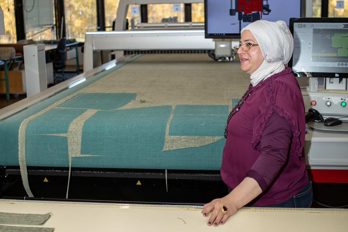 En kvinna står vid en tygbeskärningsmaskin.