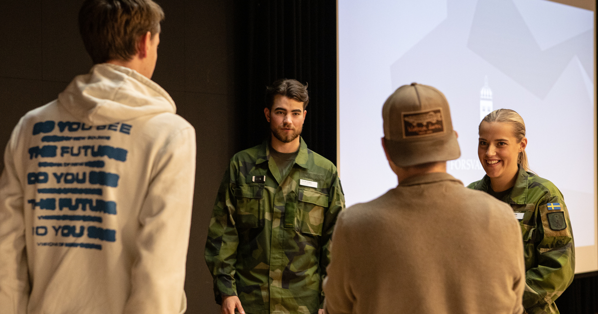 En man och kvinna i militäruniform pratar med två gymnasieelever.