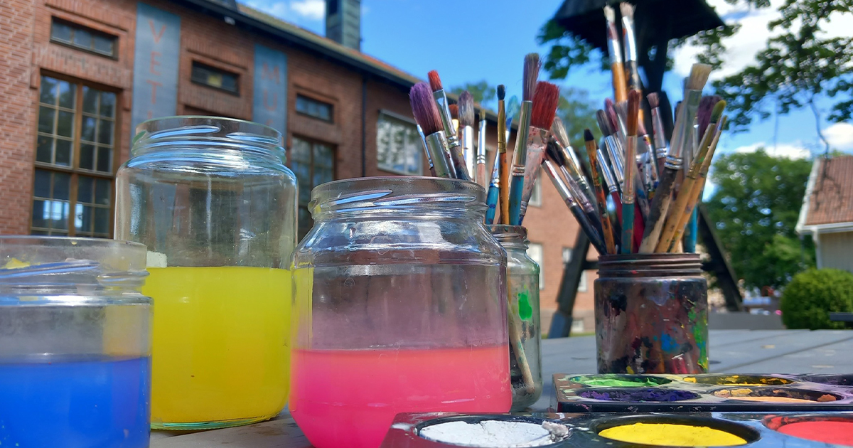 Akvarellfärg och penslar under en blå sommarhimmel i Apoteksparken