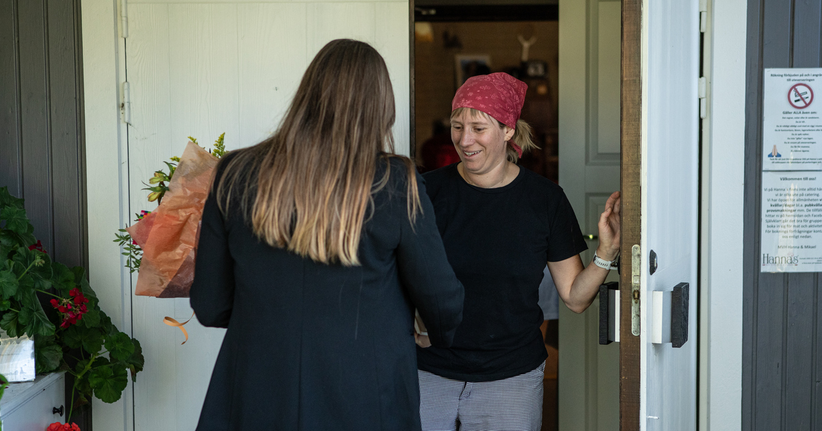 En kvinna står i en dörröppning och blir överraskad med en blombukett.