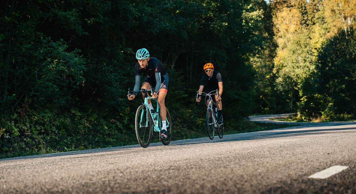 Två cyklister cyklar på en landsväg