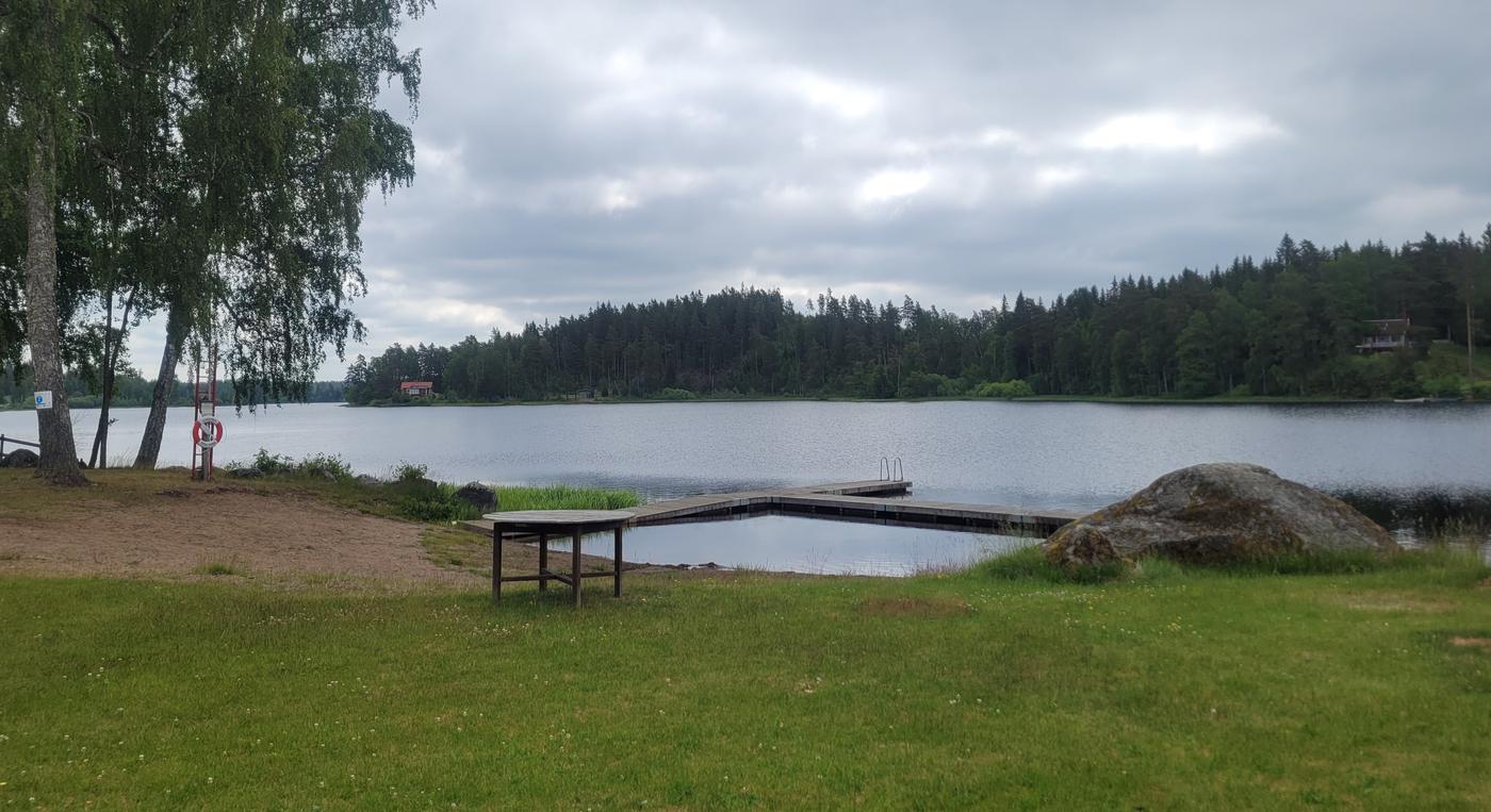 En brygga ligger i vattnet vid en liten badplats på landsbygden