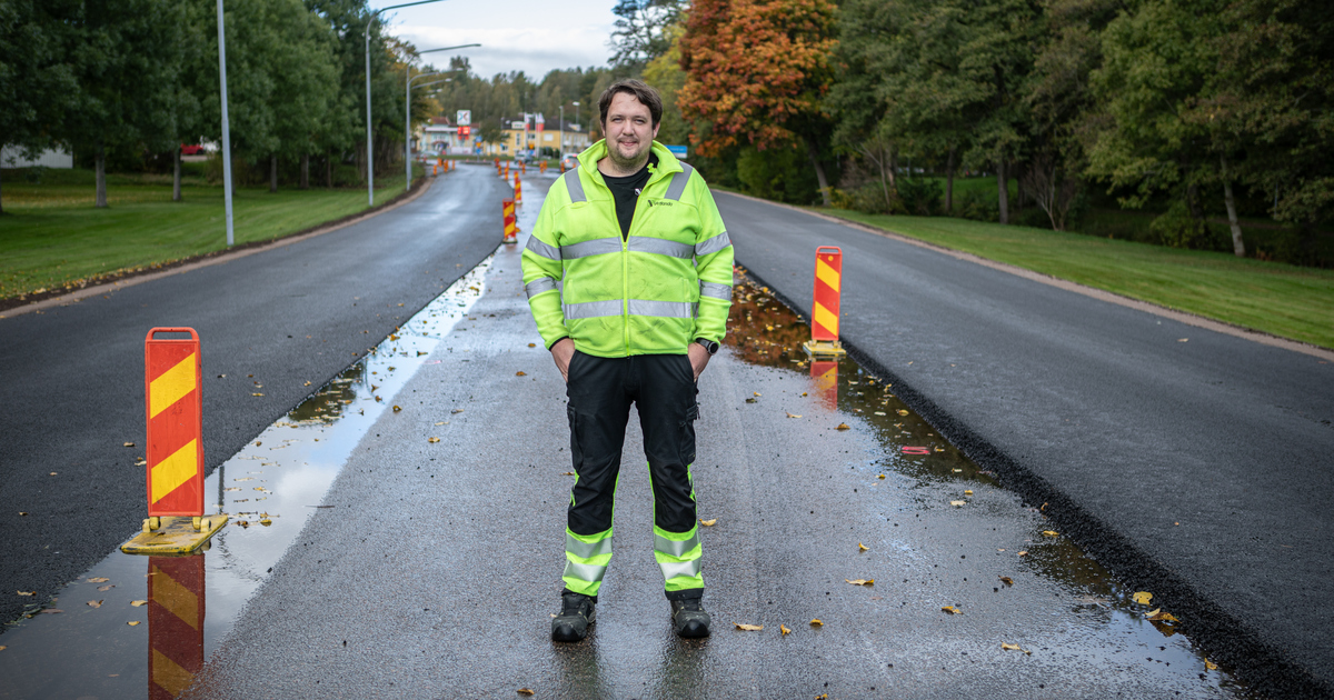 En man med varselkläder står på en avstägd väg.