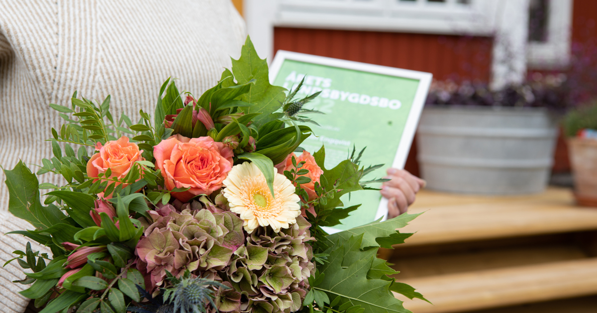 En kvinna som håller en bukett blommor och ett diplom i händerna.
