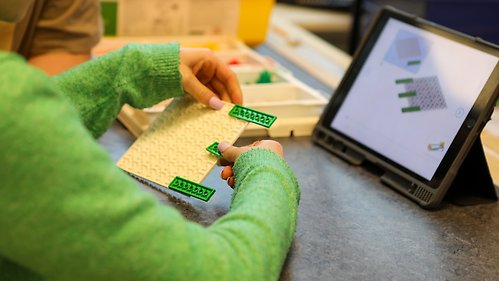 Ett barn bygger med lego och programmerar på en surfplatta