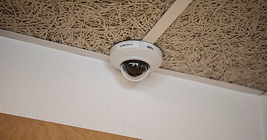 En övervakningskamera monterad i taket i ett rum.